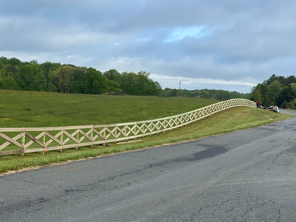 Long cross-buck wood fence along a roadside field in Meadowbrook.