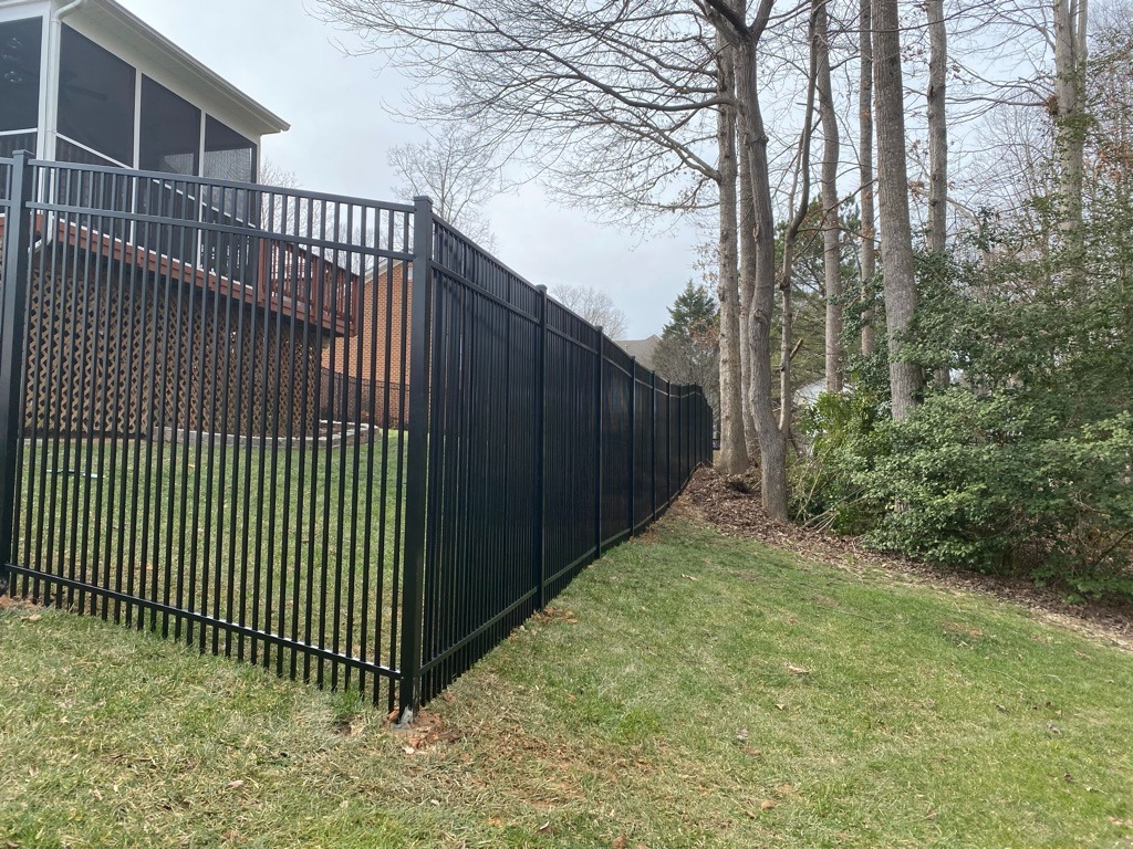 Black aluminum fence following a sloped yard for secure and stylish property boundaries in Dinwiddie, VA.